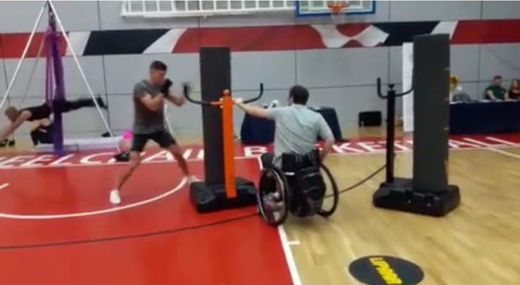 A wheelchair user holding and moving an iSPARR bag for a standing boxer